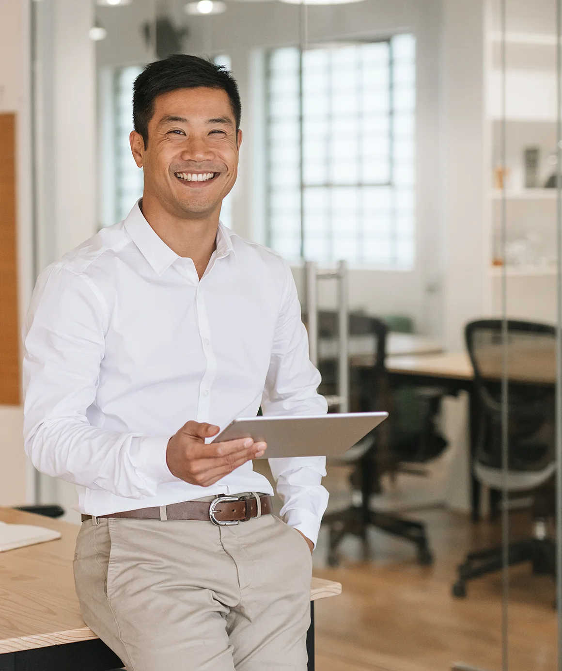 portrait of a smiling young asian businessman leaning on his desk