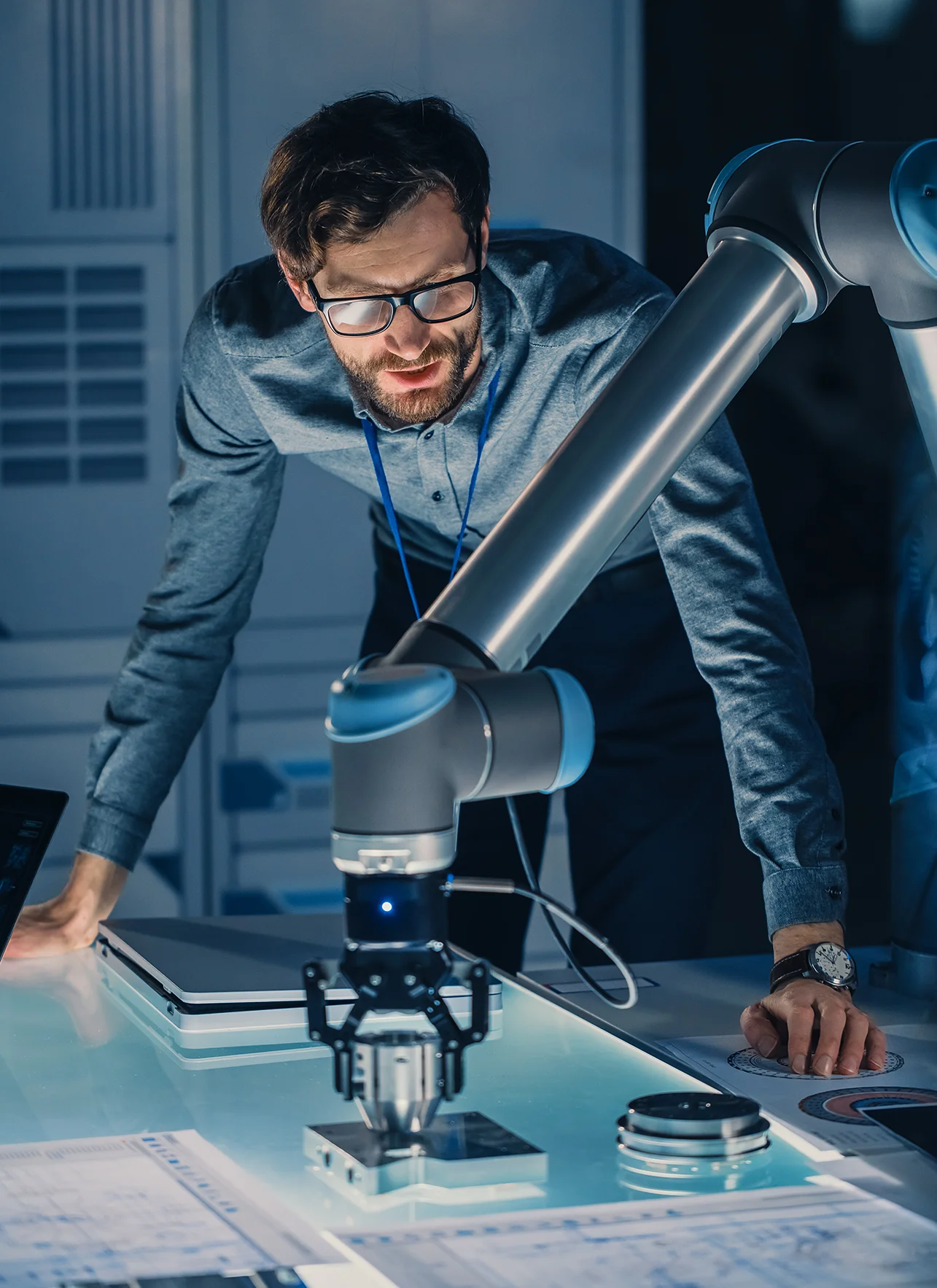 Vertical Shot of a Mechanical Engineer Works with Futuristic Robotic Arm vertical shot of a mechanical engineer works with futuristic robotic arm