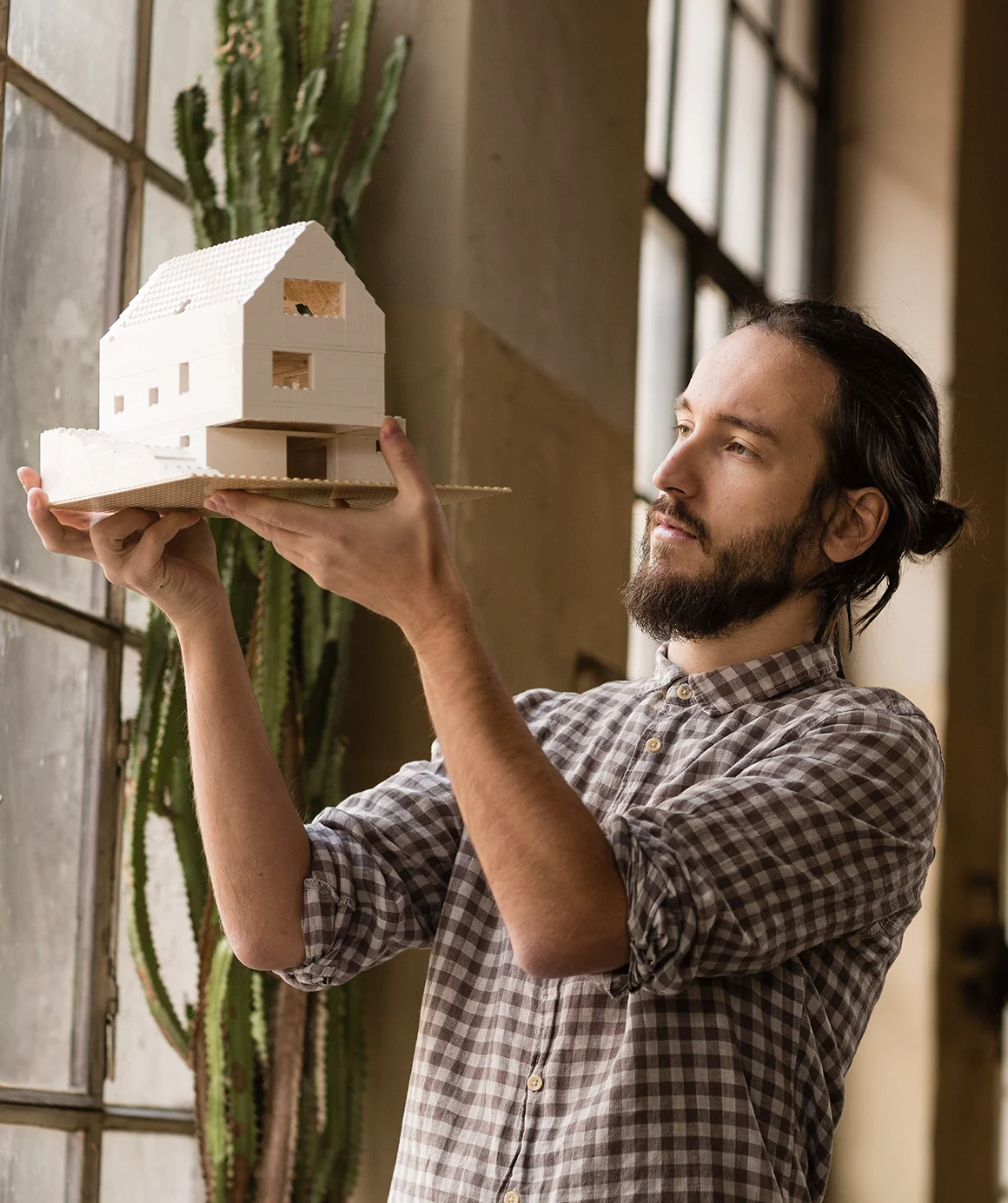Young architect is looking on the new model in the old industrial space young architect is looking on the new model in the old industrial space